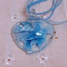 This beautiful piece is a Hand-blown Heart Shaped Glass Pendant with a Blue Flower  on the inside on a Multistrand Blue Ribbon and Corded Necklace. No maker's mark found. Used but in excellent condition. Length of the necklace is approximately 19 1/2 with the built-in extension. Adjustable. Blue Glass Flower Shaped Jewelry, Blue Flower Shaped Glass Jewelry, Blue Flower-shaped Glass Jewelry, Light Blue Glass Jewelry For Gifting, Light Blue Glass Jewelry Gift, Light Blue Glass Jewelry For Gifts, Unique Blue Heart Pendant Necklace, Unique Blue Heart-shaped Necklace, Corded Necklace