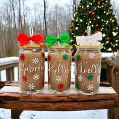 three decorated mason jars sitting on top of a wooden table in front of a christmas tree