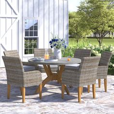 an outdoor table and chairs set up in front of a barn