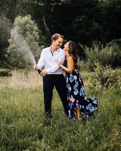 a man and woman are standing in the grass with sprinkles coming out of their mouths