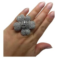 This fun flower ring contains top quality pave set round brilliant cut diamonds weighing approximately 13.00 carats total. Mounted in 18 karat white gold, this ring is the perfect whimsical touch for your collection. Stamp: 18K. Ring Size: 6 1/2 Material: 18 karat white gold Gross weight: 26.50 dwt. Diamond Characteristics (insofar as the mounting permits): Color: F-G. Clarity: VS1-VS2. Luxury Multi-stone Diamond Flower Ring, Womens Jewelry, Diamond Flower, Flower Ring, Round Brilliant Cut Diamond, Brilliant Cut Diamond, Womens Jewelry Rings, Statement Ring, Round Brilliant