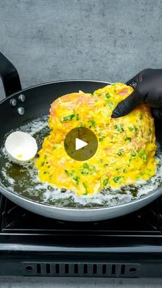 someone in black gloves is frying omelette on a stove top with an egg