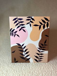 a small square painting with leaves on it