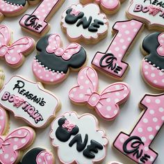 decorated cookies are arranged in the shape of minnie mouses first birthday numbers and bows