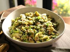 a white bowl filled with broccoli and other food on top of a table