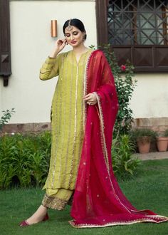 a woman in a green and red outfit standing on grass with her hand to her ear