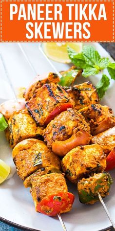 grilled chicken skewers on a plate with lemon wedges and garnishes