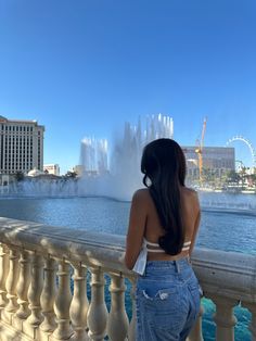 a woman is looking at the water fountain