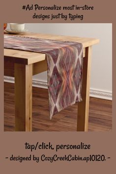 a wooden table topped with a purple and red patterned table runner next to a bowl of fruit