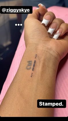 a woman's hand with a small tattoo on her left wrist and the words stamped below it