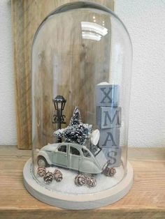 a car under a glass dome with pine cones on the bottom and a christmas tree inside