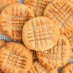 a pile of peanut butter cookies sitting on top of a white plate with holes in the middle