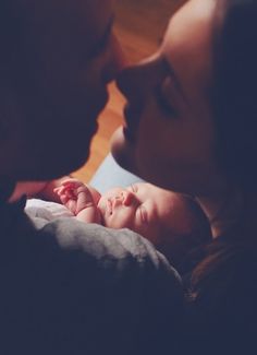 a woman holding a baby in her arms and kissing it's face to the side