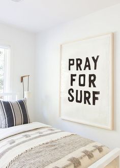 a bedroom with a white bed and black and white artwork on the wall above it