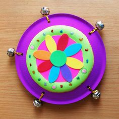 a purple plate with a colorful flower on the center and beaded bells around it