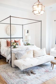 a bedroom with a four poster bed and white walls, rugs on the floor