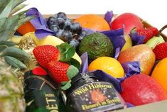 a wooden box filled with assorted fruit and wine bottles next to a pineapple