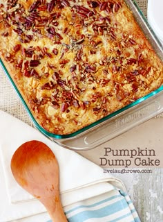 pumpkin dump cake in a glass baking dish with a wooden spoon next to it on a blue and white towel