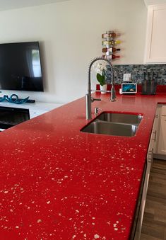 a red counter top in a kitchen next to a tv