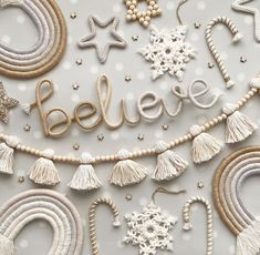 the word believe spelled out with beads and tassels on a white surface surrounded by snowflakes