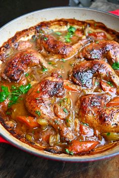 a pan filled with meat and vegetables on top of a wooden table