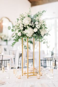 an elegant centerpiece with white flowers and greenery