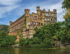 an old castle sitting on the side of a river