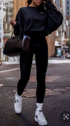 a woman in black is standing on the street