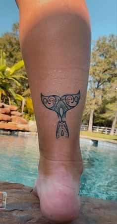 a woman's foot with a tattoo on it near a swimming pool and trees