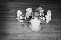 a baby is sitting on the floor surrounded by stuffed animals in black and white photo