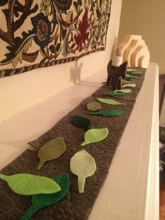 a long table topped with lots of green leafy plants next to a painting on the wall