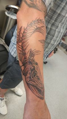 a man's arm with a fish tattoo on it, sitting in front of a chair