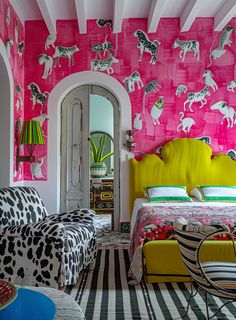 a bedroom decorated in pink and yellow with zebras on the wall