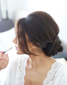 a woman is getting her make up done by another person with a brush in her mouth