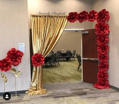 a room decorated with red flowers and gold drapes for a wedding or special event