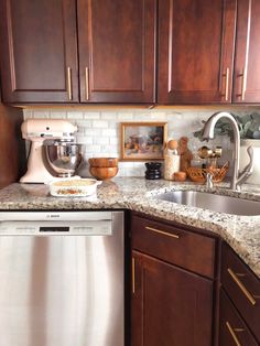 a kitchen with wooden cabinets and granite counter tops, including an appliance in the center