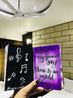 someone is holding up two books that have musical notes on them and the words behind them are written in cursive writing