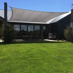 a large grassy area with picnic tables and chairs in front of a black building on a sunny day