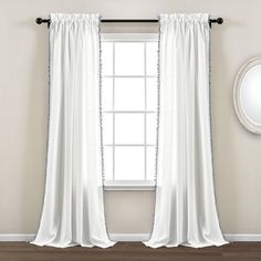 a white curtain hanging in front of a window with a mirror on the wall next to it