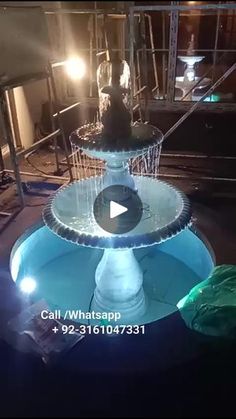 a water fountain in the middle of a building with lights shining on it's sides