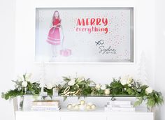 a white dresser topped with christmas decorations next to a wall mounted sign that says merry everything