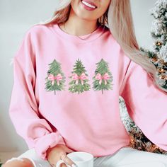 Embrace the festive spirit with our "Watercolor Christmas Trees With Pink Bows" Graphic Sweatshirt. Featuring a beautiful array of watercolor-style Christmas trees adorned with charming pink bows, this design adds a whimsical touch to your holiday wardrobe. Crafted from ultra-soft fabric, this cozy sweatshirt is perfect for all your holiday activities—from decorating the tree to enjoying cozy evenings by the fire. The vibrant colors and playful design create a cheerful vibe that will brighten up your winter days. Pair it with jeans or leggings for a cute, comfy look that spreads holiday cheer. Bring some artistic flair to your festivities with this delightful sweatshirt! 🎄🎀 Designs are printed with direct to garment, high quality ink. Christmas Lights Watercolor, Watercolor Christmas Trees, Christmas Tree Pink, Watercolor Christmas Tree, Christmas Tree Bows, Watercolor Tree, Bow Shirts, Pink Bows, Watercolor Christmas