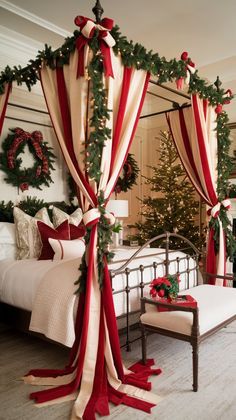 a canopy bed decorated for christmas with red and white drapes, wreaths and garland