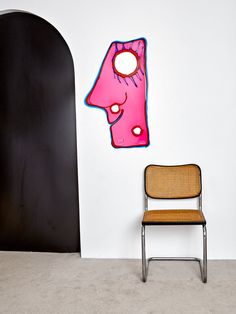 a chair sitting in front of a wall with a painting on it's side