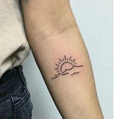 a woman's arm with a small sun tattoo on the left side of her arm