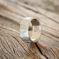 the wedding ring is sitting on top of a wooden table with an engraved message in it