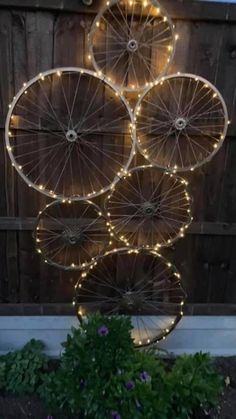 some lights that are hanging from the side of a fence in front of a wooden fence