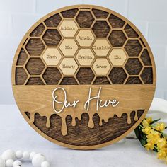 a wooden plaque that says our hive on it with honeycombs and flowers in the background