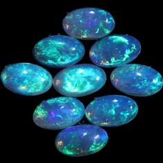 six opal stones sitting on top of each other in a black background with white and green colors