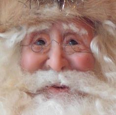 a close up of a santa clause wearing glasses and a hat with tinsel on his head